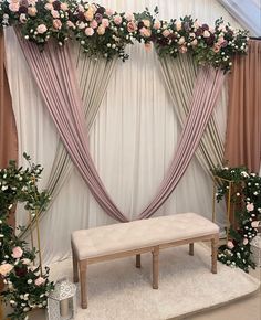 a white bench sitting under a window covered in flowers and greenery next to a wall