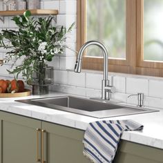 a kitchen sink sitting under a window next to a counter top with fruit on it