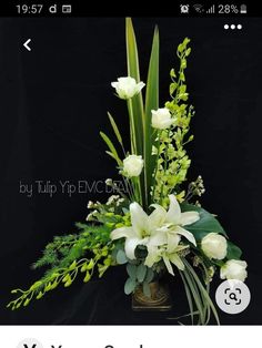 an arrangement of white flowers and greenery in a vase