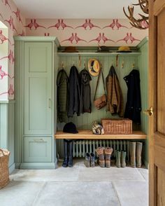 a coat rack with coats and boots hanging on the wall next to an open door