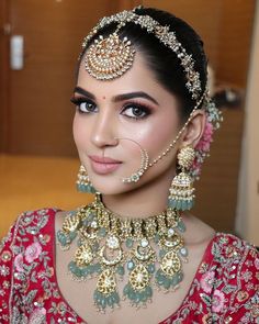 a woman in a red and gold outfit with jewelry on her head, looking at the camera