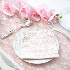 the table is set with pink flowers and silverware