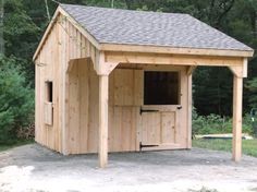 a small wooden shed sitting on top of a dirt field next to trees and bushes