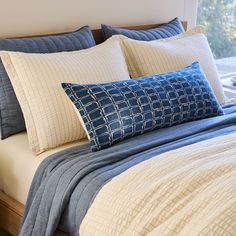 a bed with blue and white pillows on it