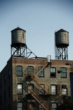 an old brick building with two water towers on top and a set of stairs leading up to the second floor