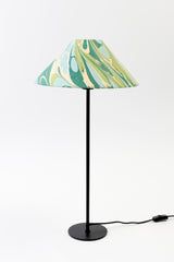 a lamp that is on top of a white surface with a green and blue shade