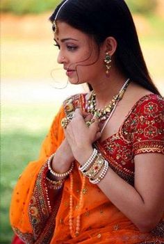 a woman in an orange sari and jewelry