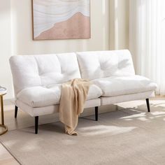 a white couch sitting on top of a rug in a living room next to a window