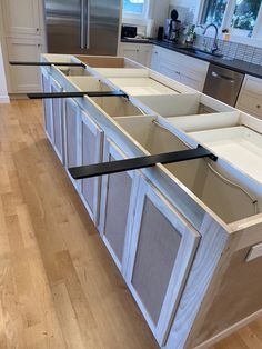 a kitchen with white cabinets and black trim on the bottom drawer, along with stainless steel appliances