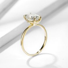 a yellow gold engagement ring with an oval cut diamond in the center, on a white background