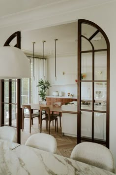 an open kitchen and dining room area with marble counter tops, white walls and wood trimming