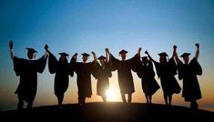 a group of graduates standing on top of a hill with their arms in the air