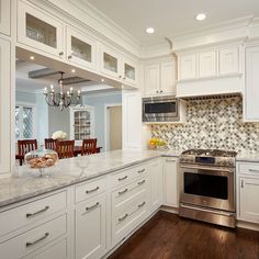 a large kitchen with white cabinets and marble counter tops, along with an oven and dishwasher