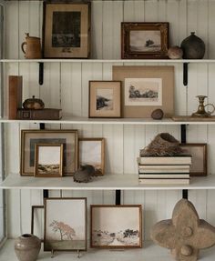 a shelf with pictures and other items on it in a room that is painted white