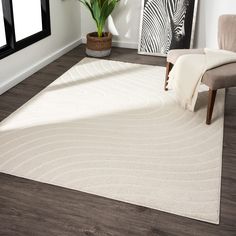 a large white rug in a living room next to a chair and potted plant