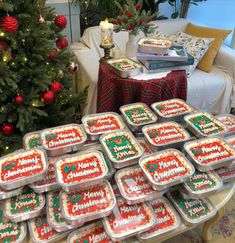 a table topped with lots of cake covered in frosting next to a christmas tree