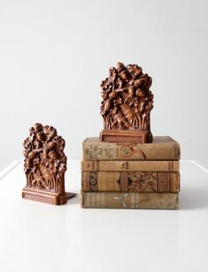 two books are stacked on top of each other, one is carved with flowers and leaves