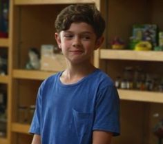 a young boy is standing in front of shelves