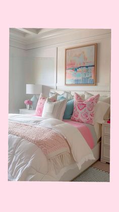 a white bed topped with lots of pillows next to a pink and blue painting on the wall