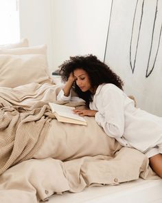 a woman laying in bed reading a book