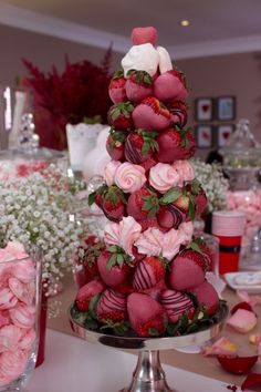 a cake made to look like strawberries with roses and hearts on the top tier