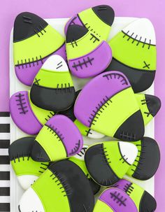 decorated cookies in the shape of footballs on a white plate with purple and green icing