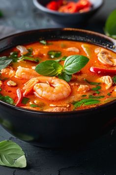 a bowl of soup with shrimp, tomatoes and basil