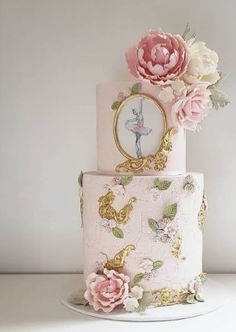 a three tiered cake decorated with pink flowers and an embroidered figure on the top