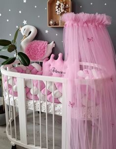 a baby's crib with pink bedding and decorations on the wall behind it