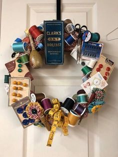 a wreath made out of yarn and sewing supplies is hanging on the front door with a book