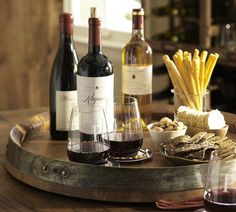 three bottles of wine and two glasses of wine on a table with cheese, crackers and bread