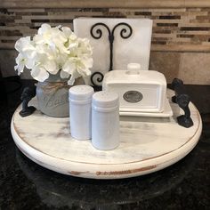 white flowers in a vase sitting on top of a table next to two salt and pepper shakers