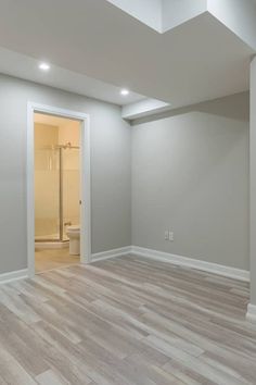 an empty room with white walls and wood floors is shown in this image, there are lights on either side of the door