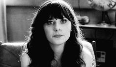 black and white photo of woman with long hair sitting in chair looking at the camera