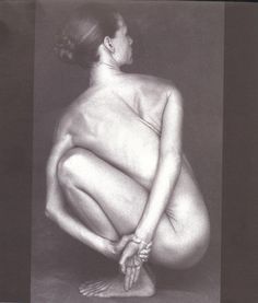 a nude woman sitting on the ground with her legs crossed