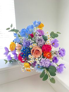 a bouquet of colorful flowers sitting on top of a window sill