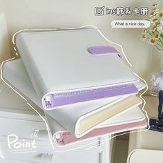 three binders are stacked on top of each other in front of a white dresser