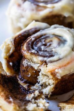 cinnamon rolls with icing on top sitting on a plate