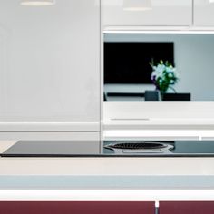 a modern kitchen with white cabinets and stainless steel stove top burner, in the foreground is a vase with flowers