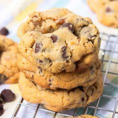 chocolate chip cookies stacked on top of each other in front of a cooling rack full of them