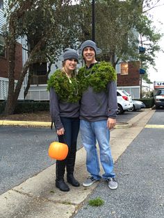 a man and woman standing next to each other in front of a street with trees