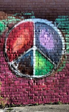 graffiti on the side of a brick building with a peace sign painted on it's side