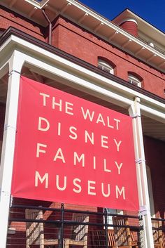 a red sign that says the walt disney family museum in front of a brick building