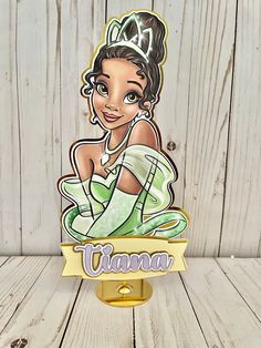 the disney princess and the frog character is shown on top of a wooden table with white plank