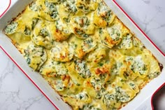 a casserole dish with spinach and cheese in it on a white table