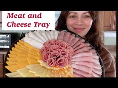 a woman holding a plate with meat and cheese tray