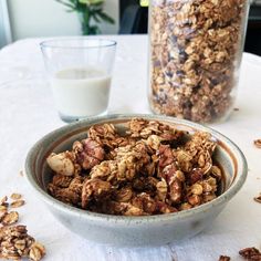 a bowl filled with granola next to a glass of milk