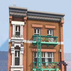 a tall brick building with green balconies on the second story and two stories