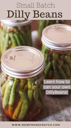 three jars filled with pickled green beans on top of a cloth covered tablecloth