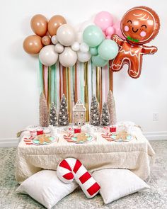 a table topped with balloons and candy canes next to a gingerbread man balloon